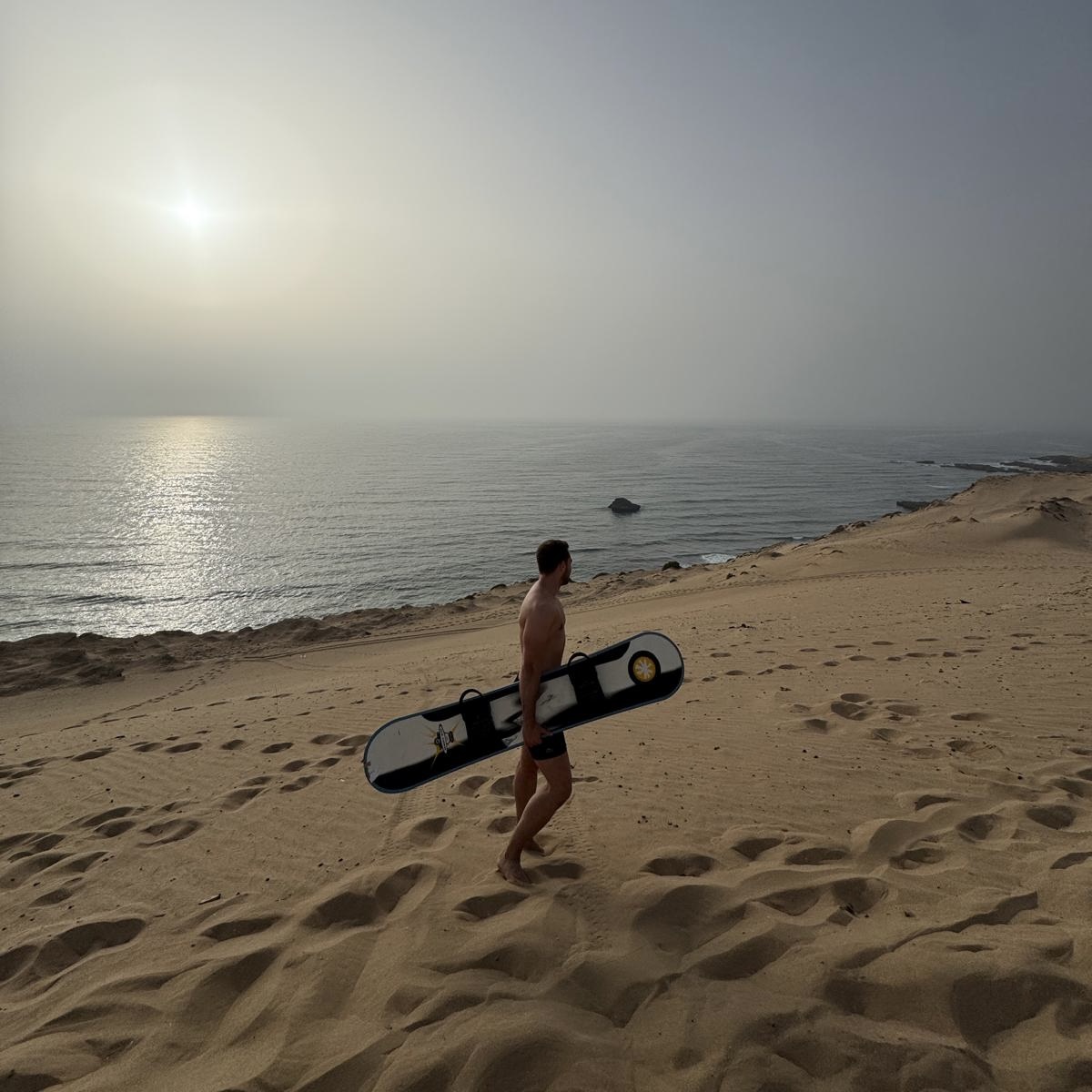 Tourist sandboarding down the Timlalin desert dunes near Agadir Morocco