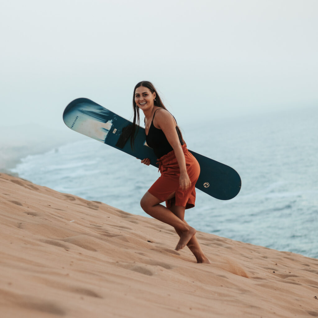 Tourist sandboarding down the Timlalin desert dunes near Agadir Morocco